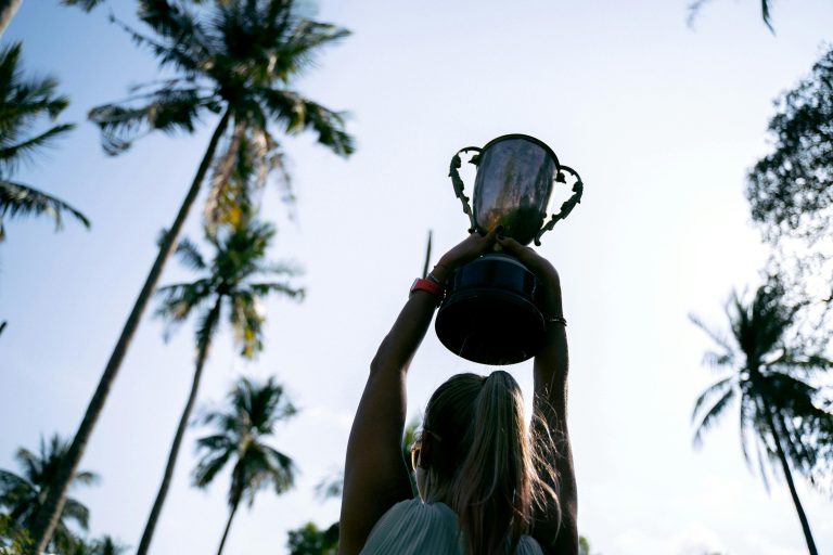 image of woman holding up trophy for blog post "what is indemnity insurance"